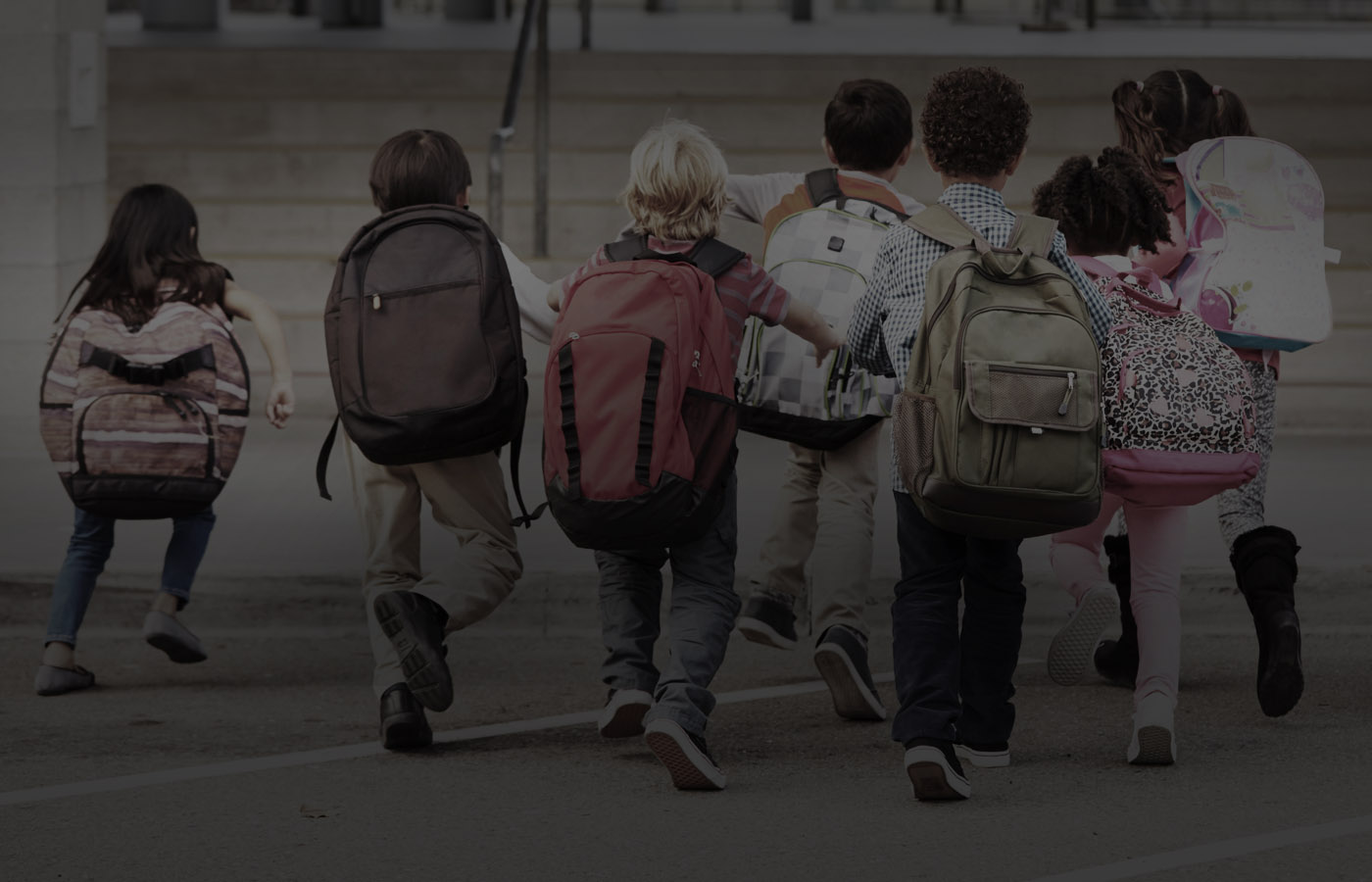 Imagen de fondo con un grupo de niños y niñas con mochilas.