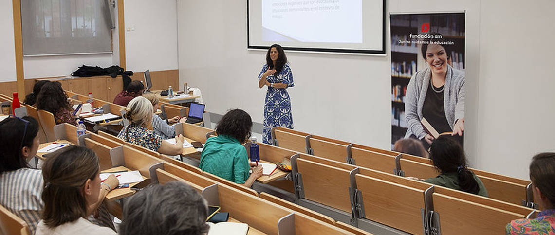 Imagen de una ponente dando una charla a alumnos en un aula.