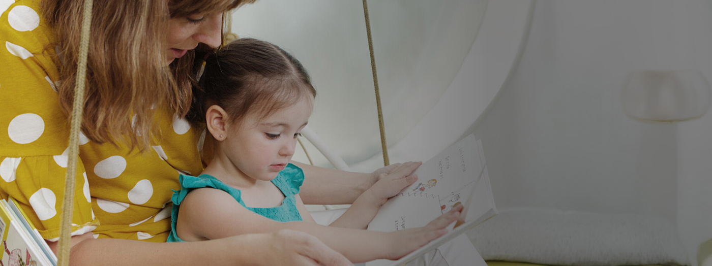 Fotografía de una madre leyendo un cuento a su hija.